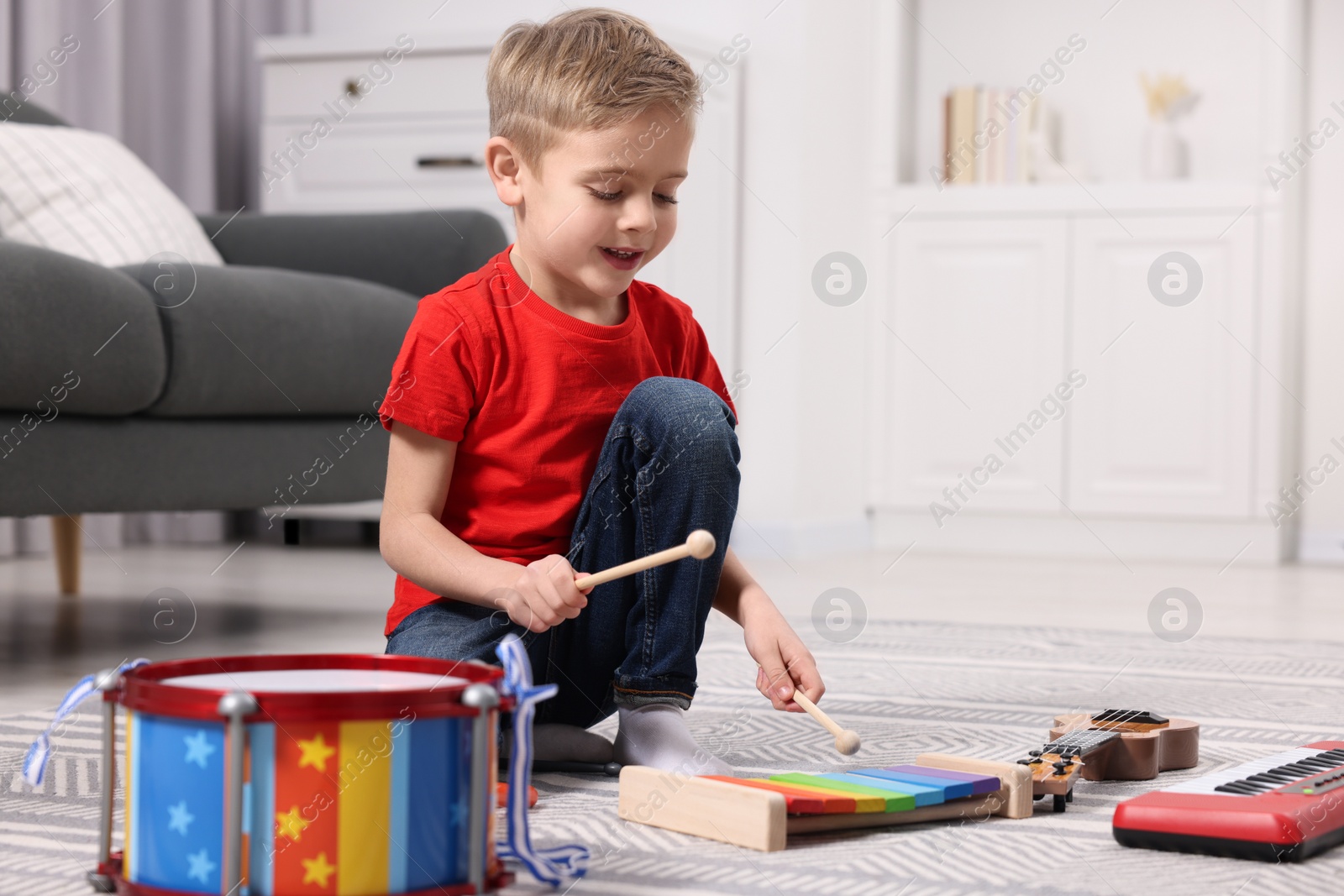 Photo of Little boy playing toy xylophone at home