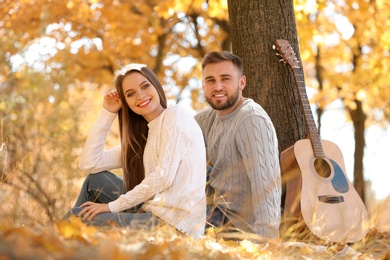 Photo of Young couple with guitar in autumn park