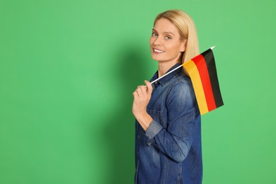 Photo of Woman with flag of Germany on green background, space for text