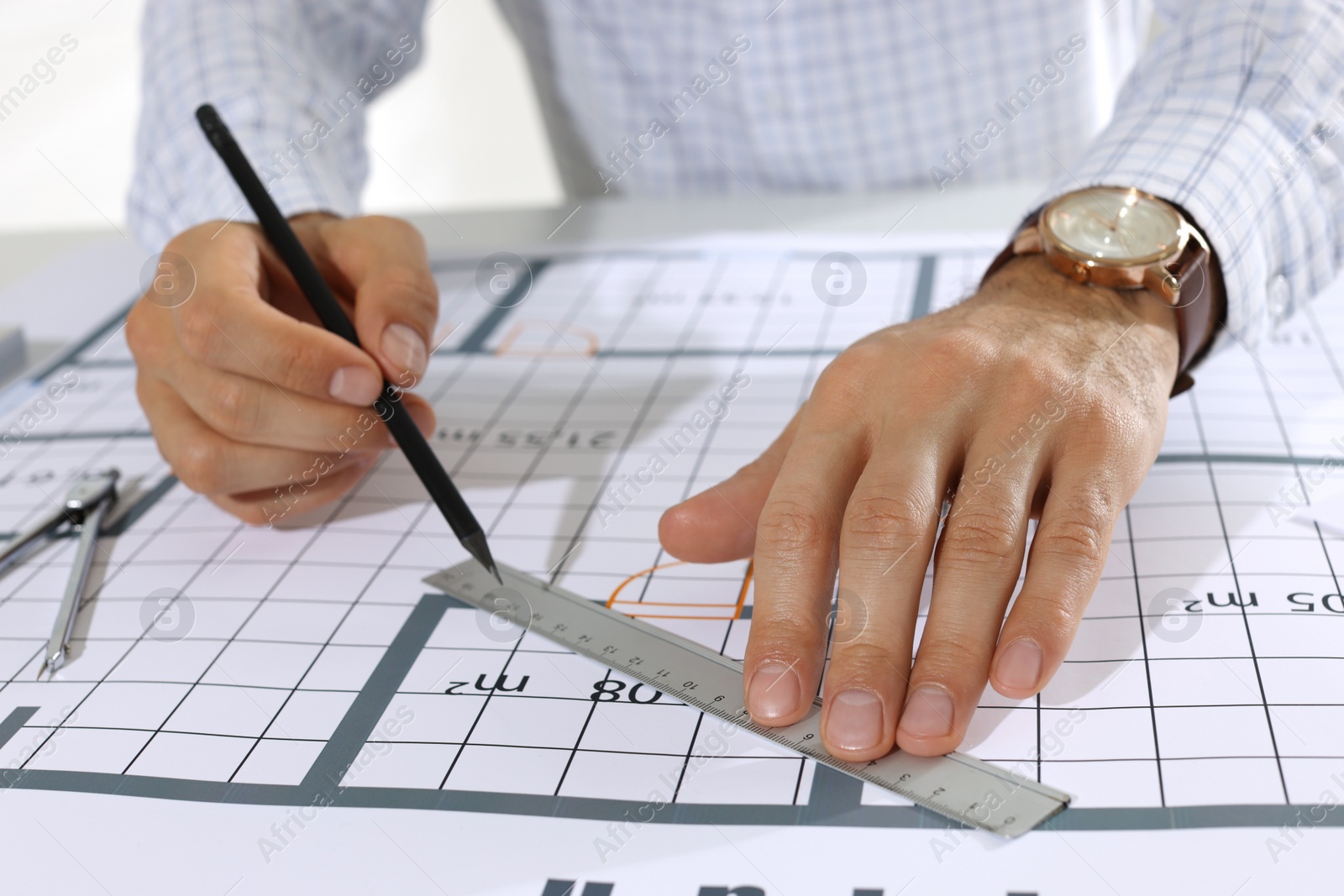 Photo of Architect working with construction drawings indoors, closeup