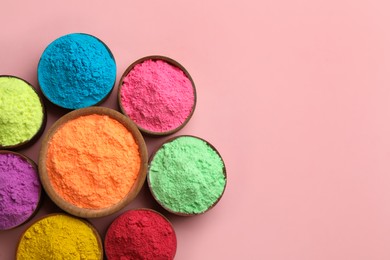 Colorful powders in bowls on pink background, flat lay with space for text. Holi festival celebration