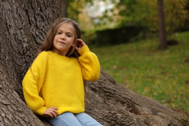 Photo of Portrait of cute girl near tree in autumn park, space for text