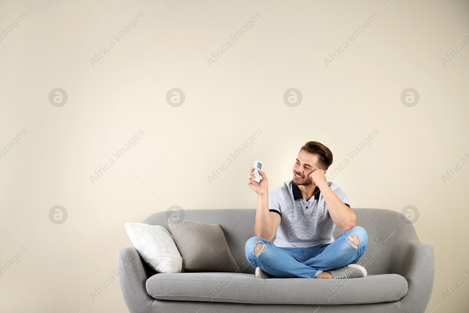 Photo of Young man with air conditioner remote at home