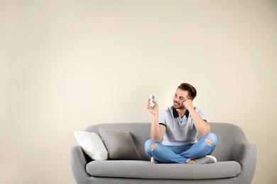 Young man with air conditioner remote at home