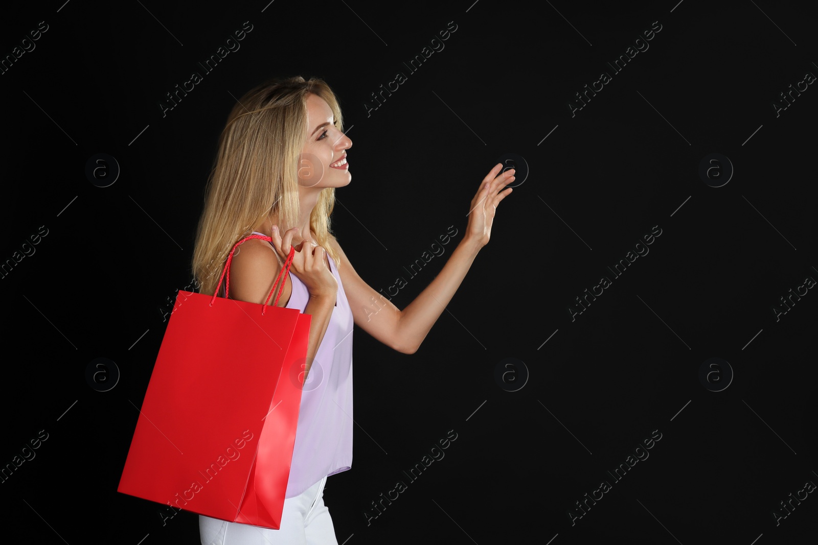 Photo of Happy young woman with shopping bag on dark background, space for text. Black Friday Sale