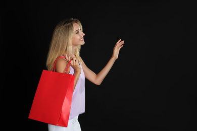 Photo of Happy young woman with shopping bag on dark background, space for text. Black Friday Sale