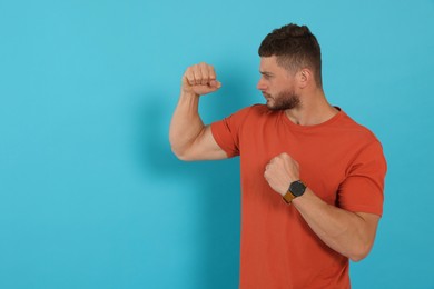 Photo of Young man ready to fight on light blue background, space for text