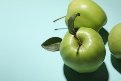 Photo of Fresh green apples on light blue background, closeup. Space for text