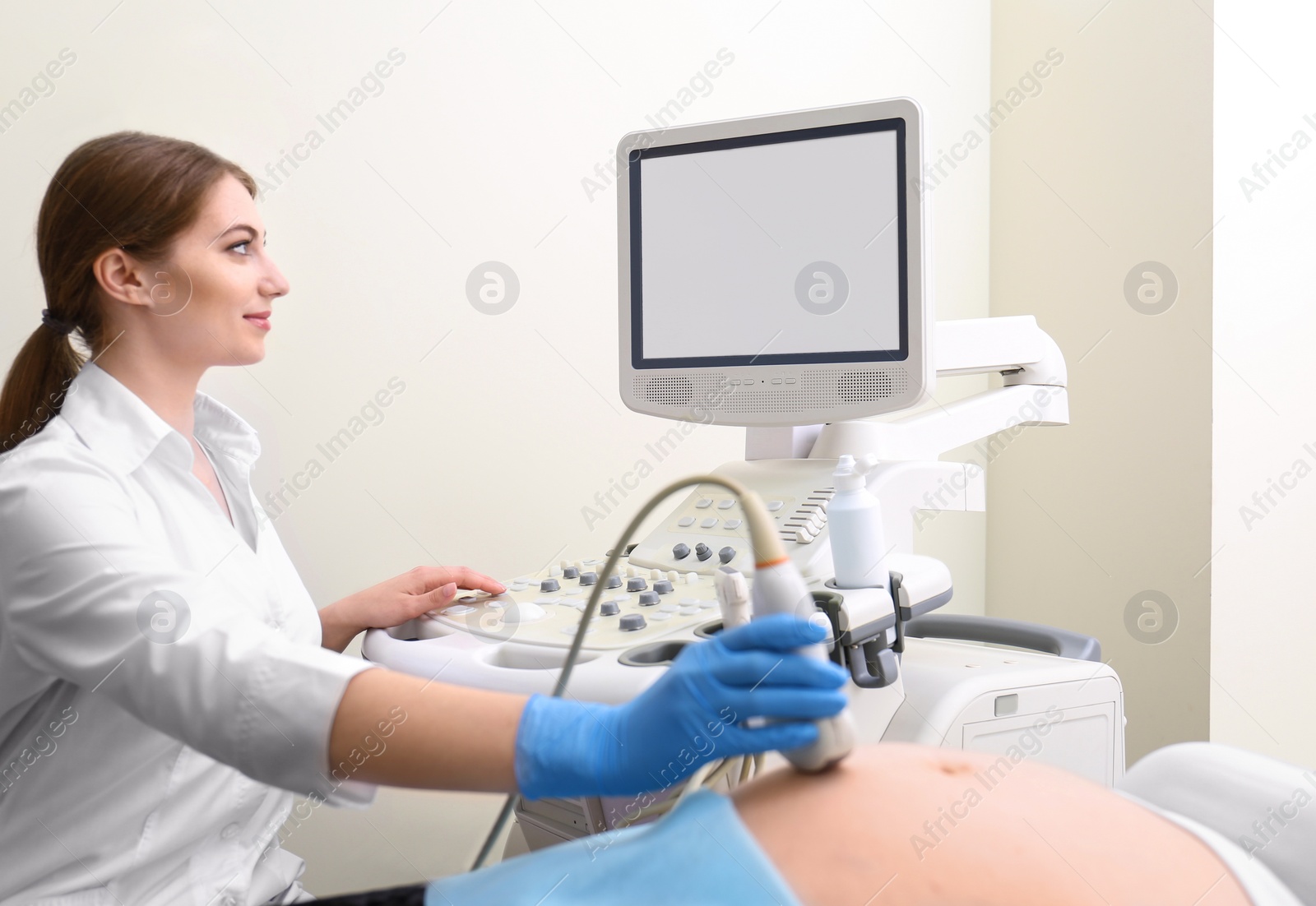 Photo of Young pregnant woman undergoing ultrasound scan in clinic