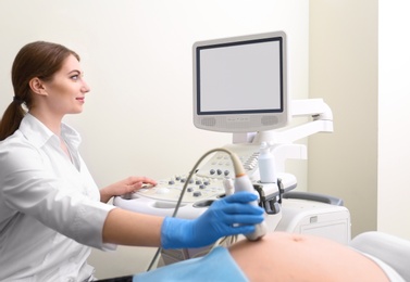 Young pregnant woman undergoing ultrasound scan in clinic