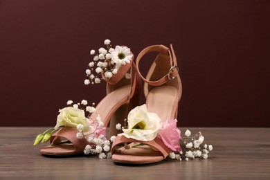 Photo of Women's shoes with beautiful flowers on wooden surface