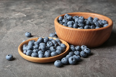 Dishware with juicy and fresh blueberries on color table