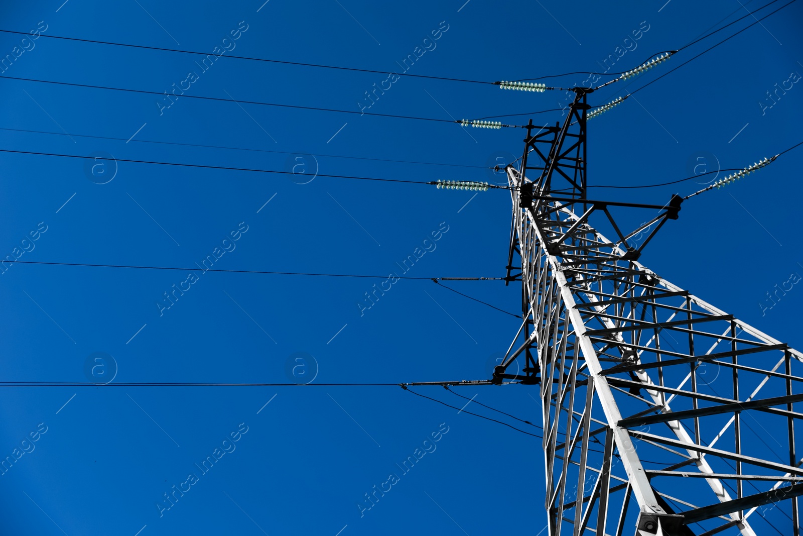 Photo of Modern high voltage tower against blue sky, low angle view