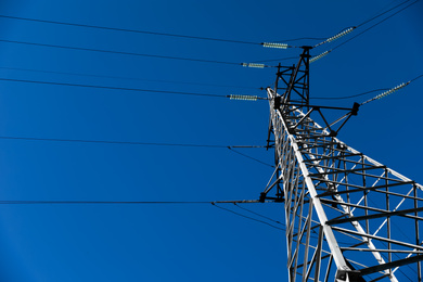 Photo of Modern high voltage tower against blue sky, low angle view