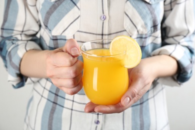 Photo of Woman holding cup of immunity boosting drink in hands, closeup