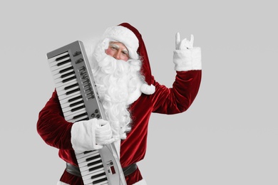 Photo of Santa Claus with synthesizer on light grey background, space for text. Christmas music