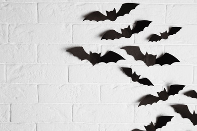 Photo of Paper bats on brick wall with space for text. Halloween decor