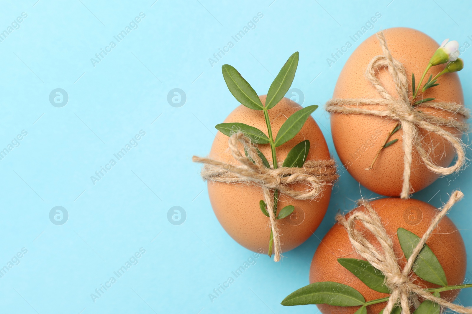 Photo of Festively decorated chicken eggs on light blue background, flat lay with space for text. Happy Easter