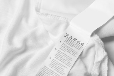 Photo of Clothing label on beautiful white garment, closeup. Space for text