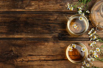 Photo of Flat lay composition with tea and chamomile flowers on wooden table. Space for text