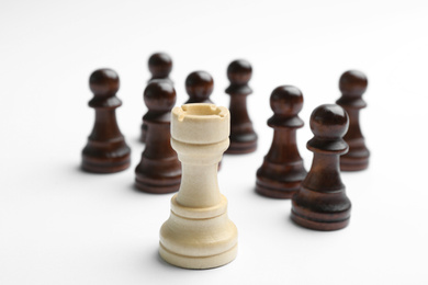 Photo of White rook in front of black pawns on light background. Career promotion concept