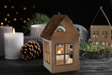 Photo of Composition with candle in house shaped holder on wooden table. Christmas decoration