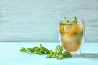 Photo of Glass with aromatic mint tea and fresh leaves on table