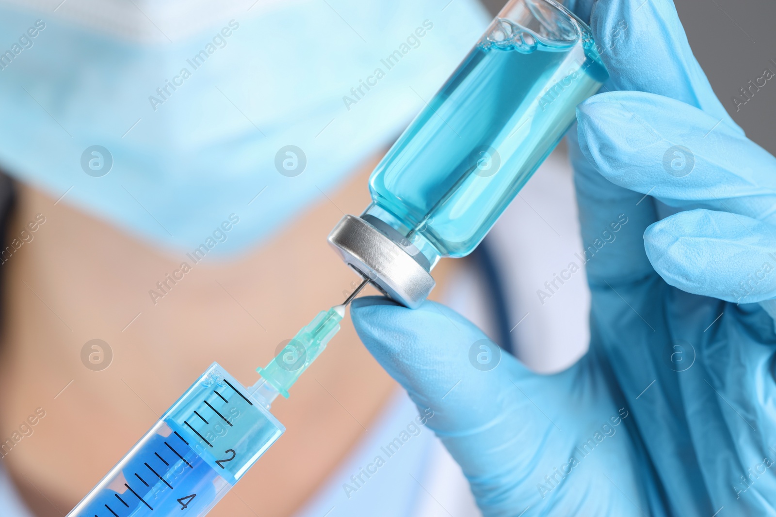 Photo of Doctor filling syringe with medication from glass vial, closeup