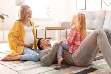 Photo of Young pregnant woman with her family at home