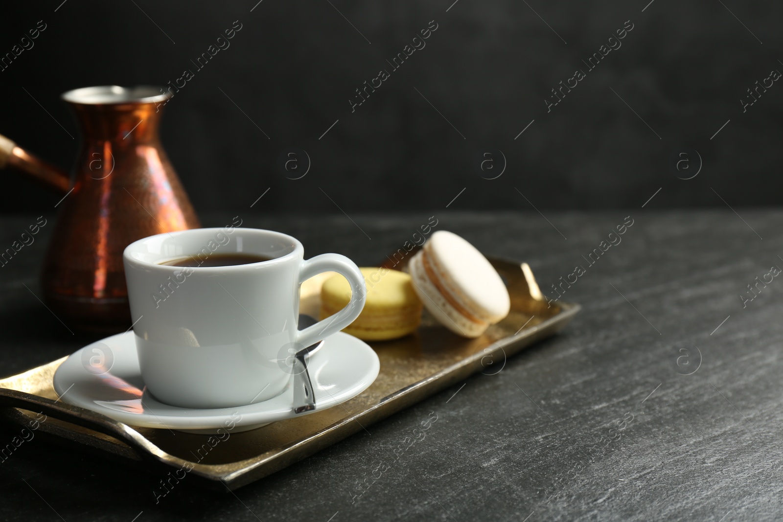 Photo of Tray with hot coffee in cup and macarons on dark textured table. Space for text