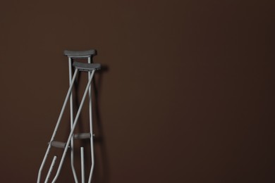 Photo of Pair of axillary crutches on brown background. Space for text