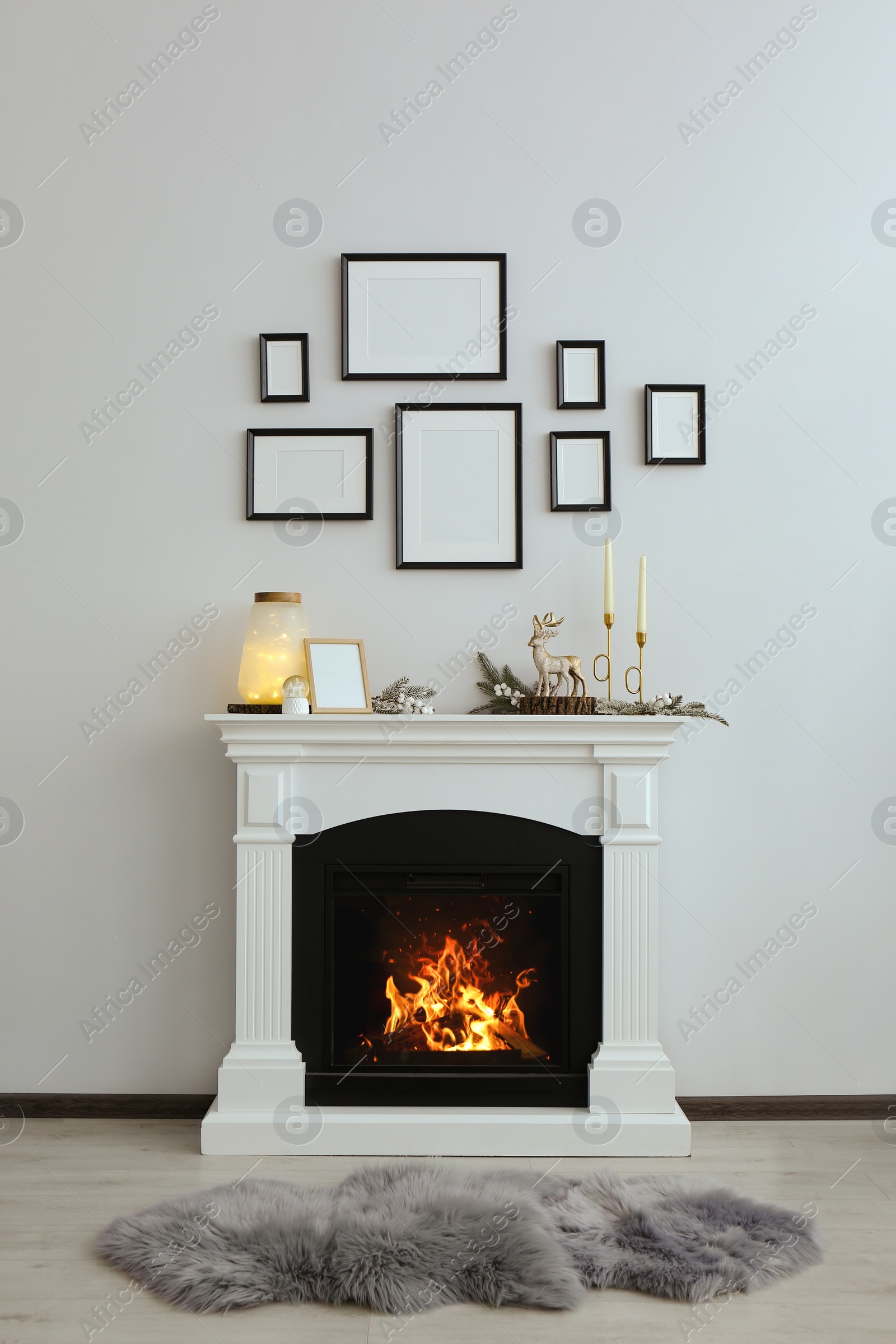 Photo of Stylish interior decorations on fireplace near white wall indoors