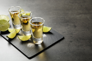 Mexican Tequila shots with salt and lime slices on grey table. Space for text