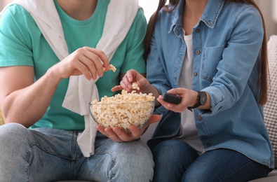 Photo of Couple watching movie with popcorn at home, closeup