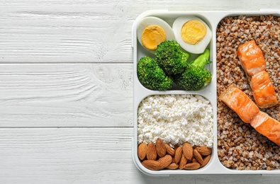 Container with natural healthy lunch and space for text on table. High protein food