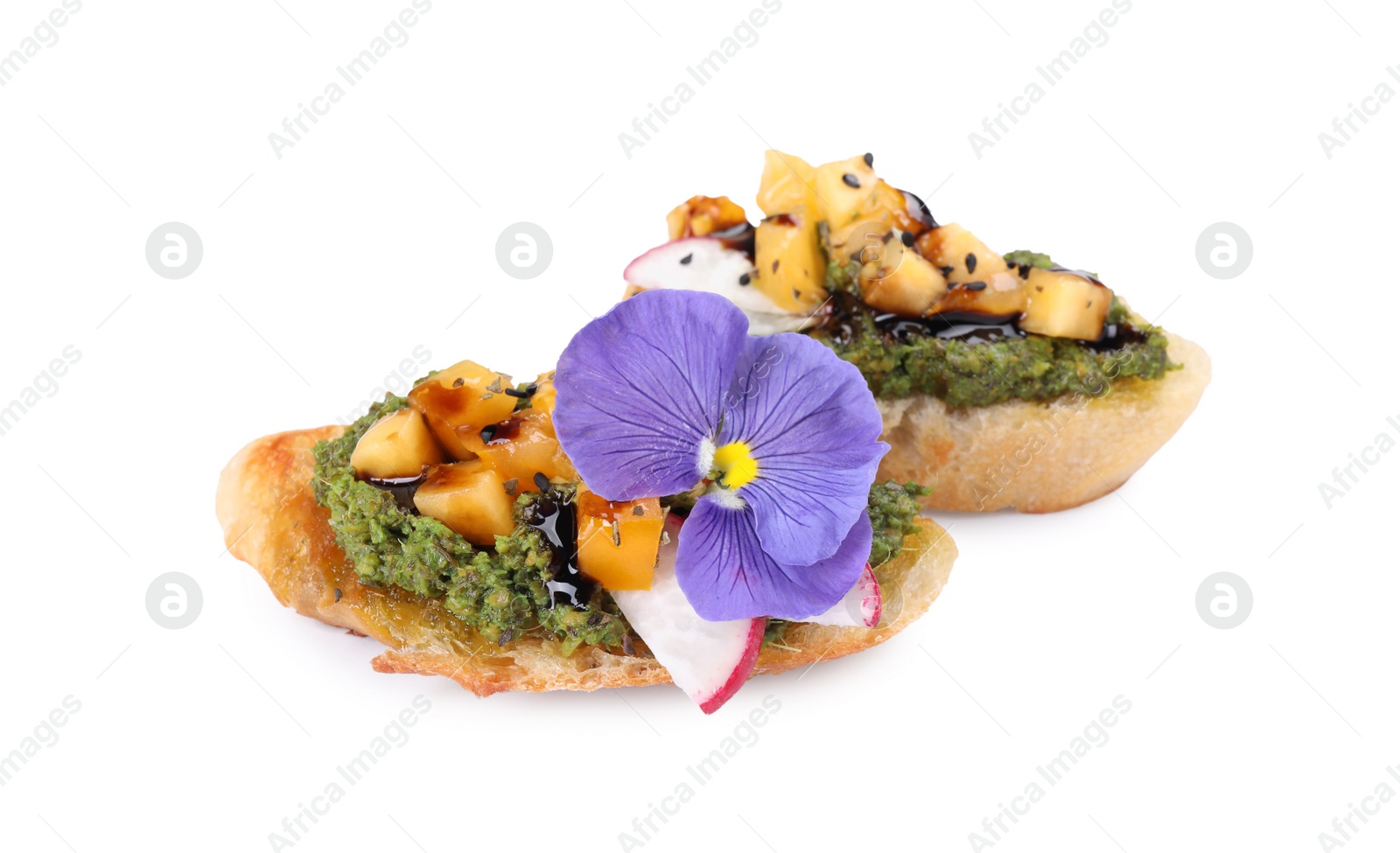 Photo of Delicious bruschettas with pesto sauce, tomatoes, balsamic vinegar and violet flower isolated on white