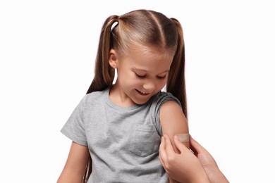 Photo of Woman sticking plaster on girl's arm after vaccination against white background