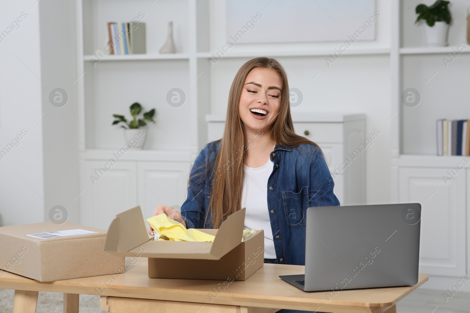 Photo of Happy woman unpacking parcel at home. Online store