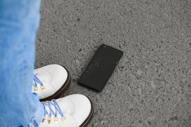 Woman near dropped smartphone on asphalt, closeup. Device repairing