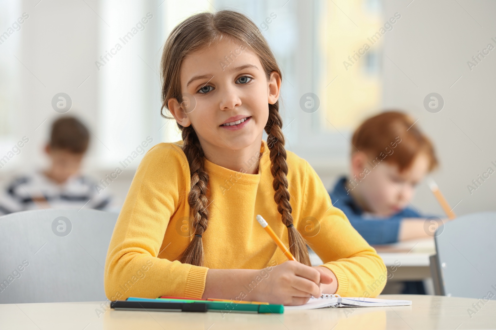 Photo of Portrait of smiling little girl studying in classroom at school