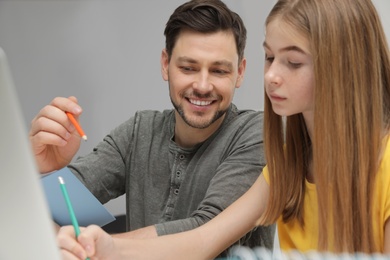 Photo of Father helping his teenager daughter with homework indoors