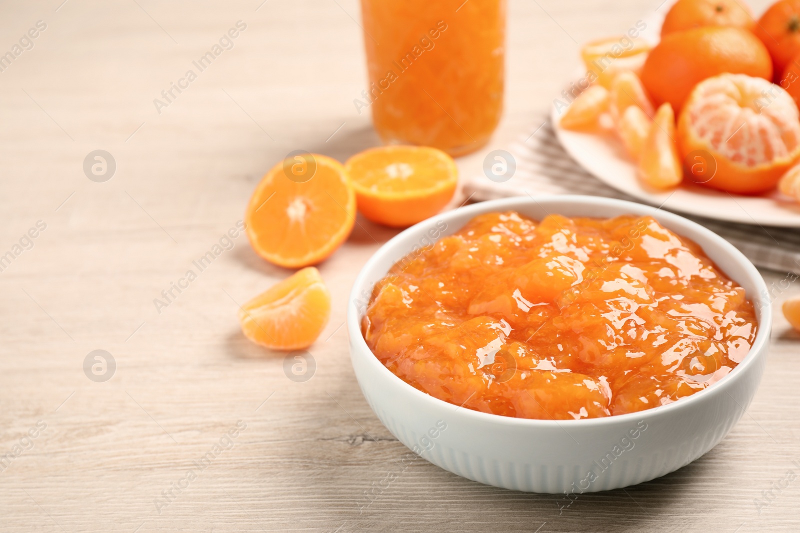 Photo of Delicious tangerine jam on wooden table. Space for text