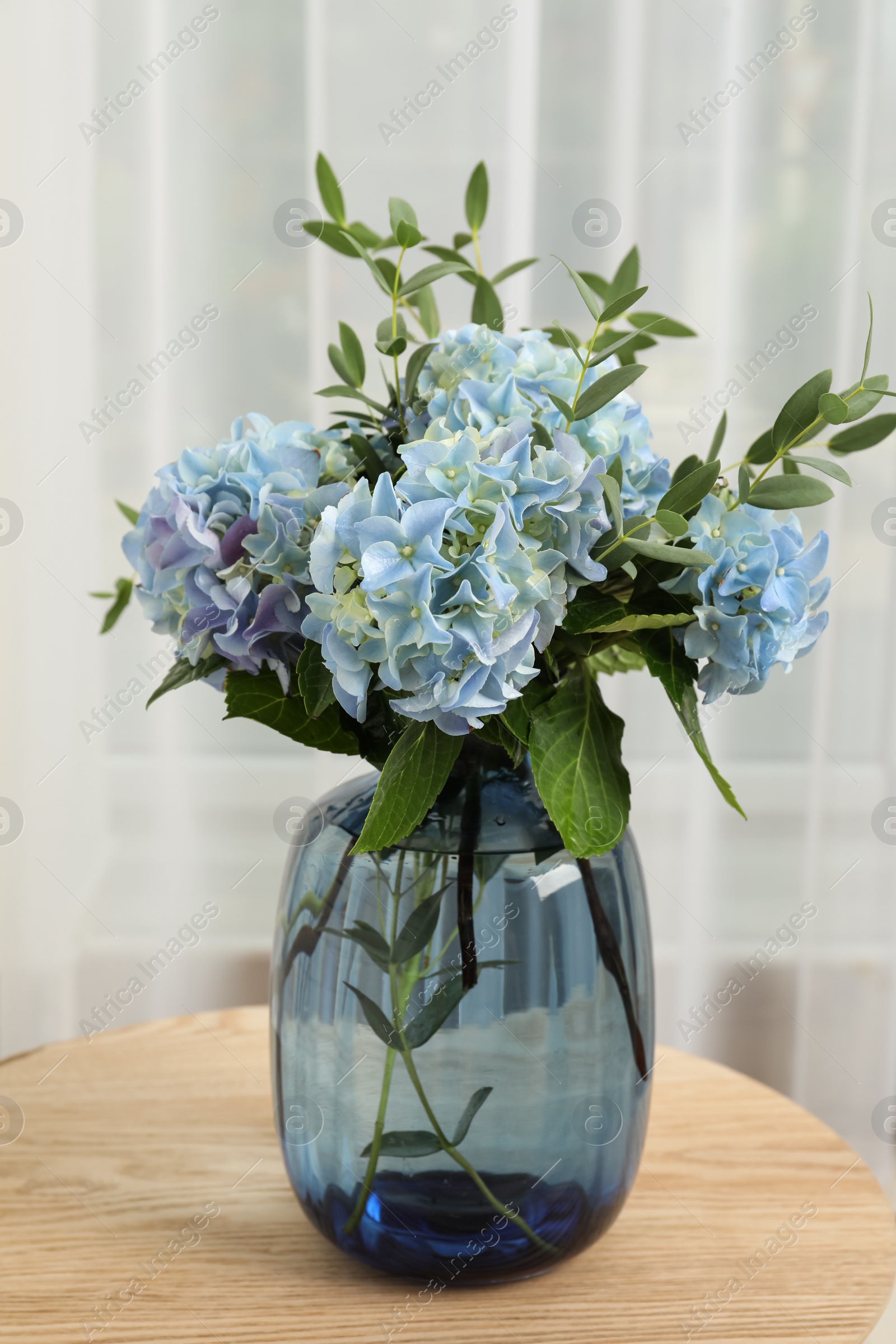 Photo of Beautiful blue hortensia flowers in vase on table indoors