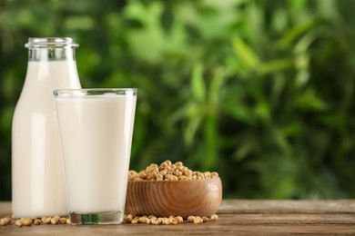 Fresh soy milk and grains on white wooden table against blurred background. Space for text