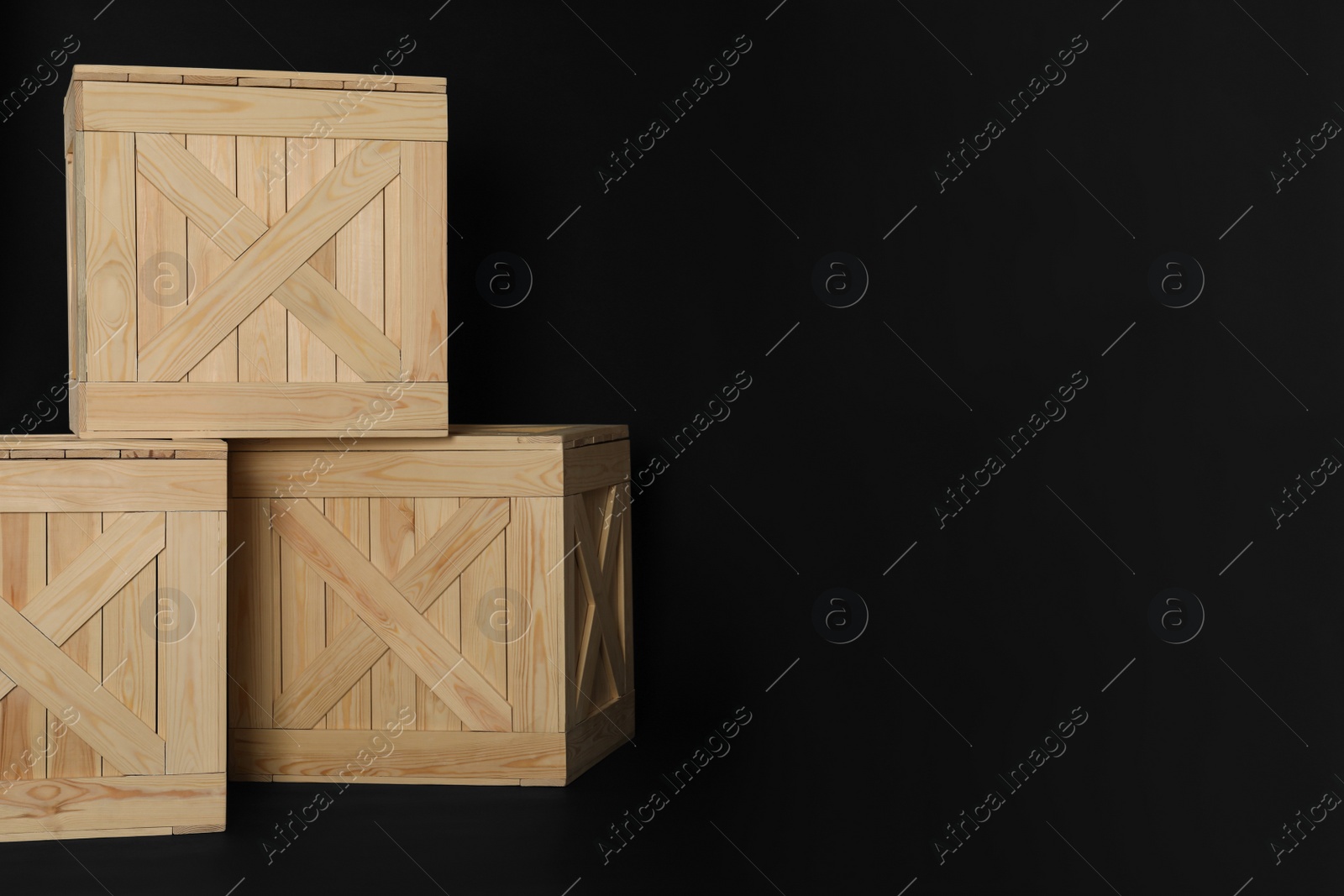 Photo of Wooden crates on black background, space for text. Shipping containers