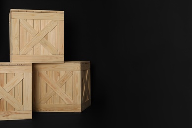 Photo of Wooden crates on black background, space for text. Shipping containers