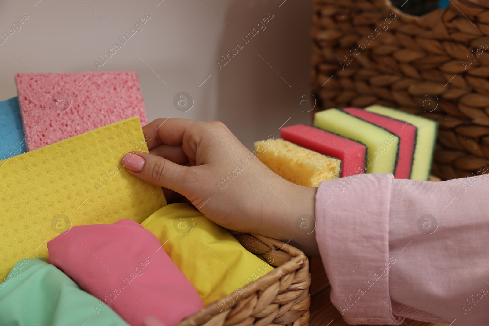 Photo of Woman taking cleaning cloth from basket indoors, closeup view