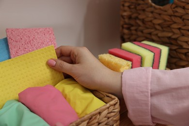 Photo of Woman taking cleaning cloth from basket indoors, closeup view