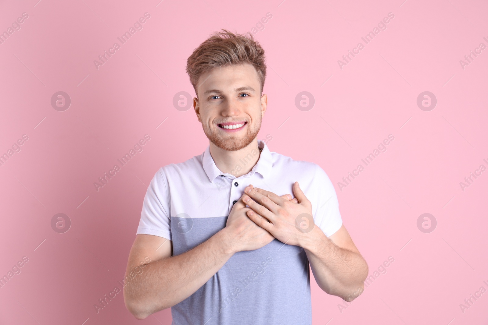 Photo of Portrait of young man holding hands near heart on color background