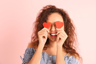 Photo of African-American woman with paper hearts on color background